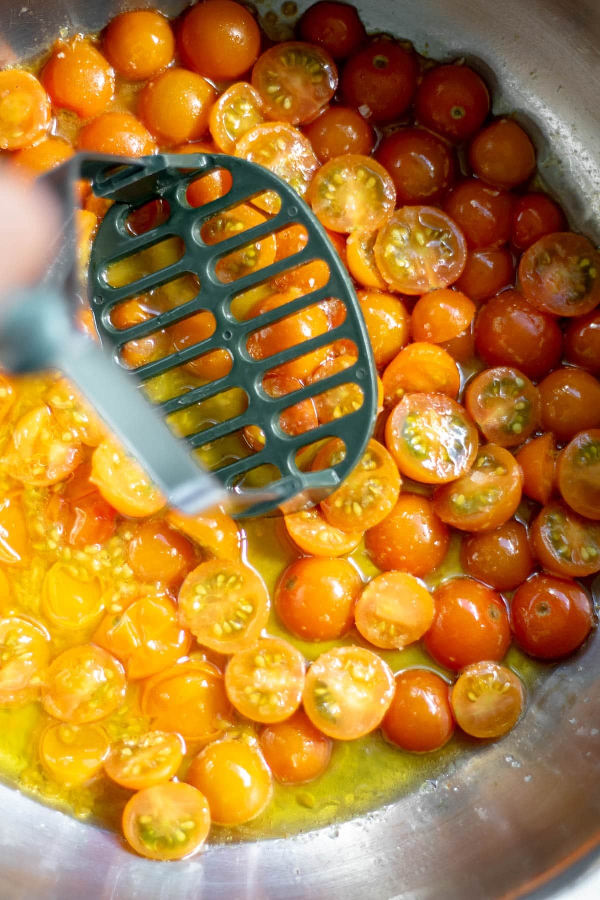 mashing sungold tomatoes in a pan
