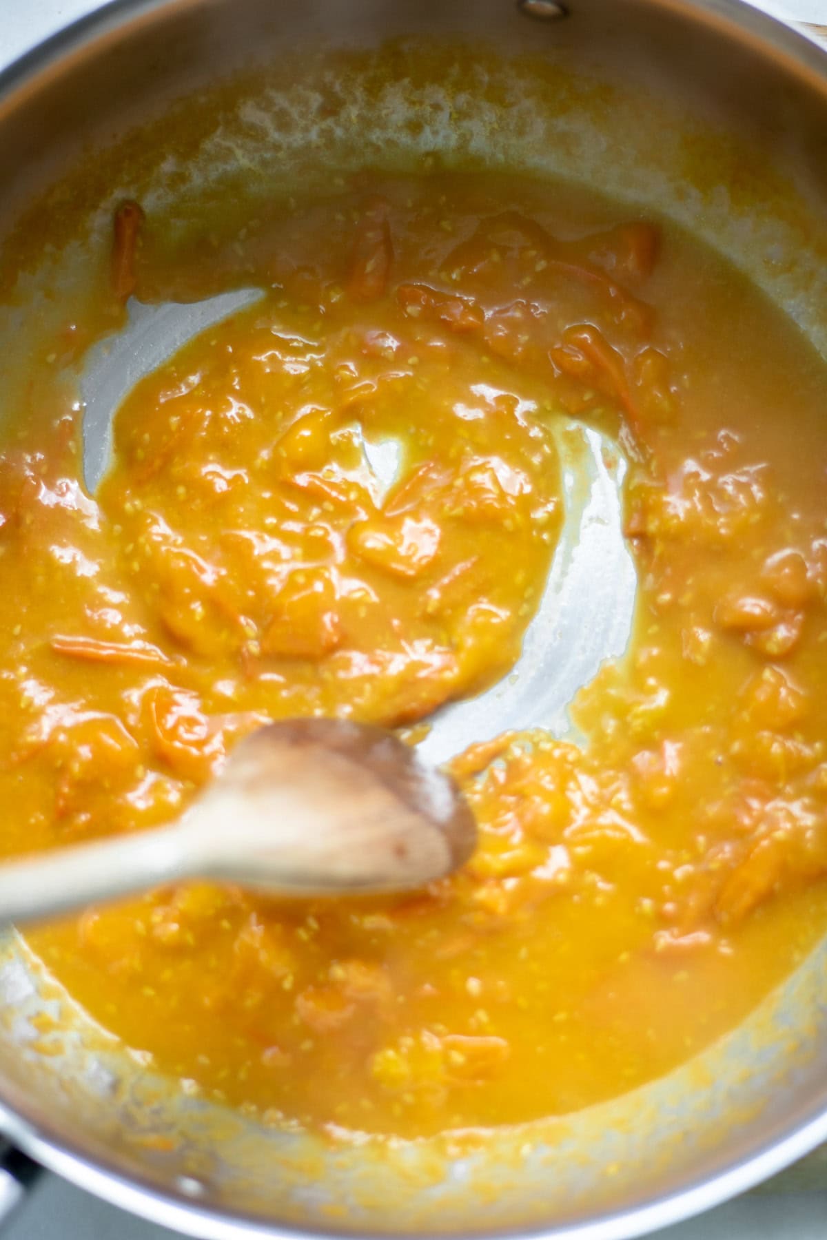 wooden spoon stirring sungold tomato sauce