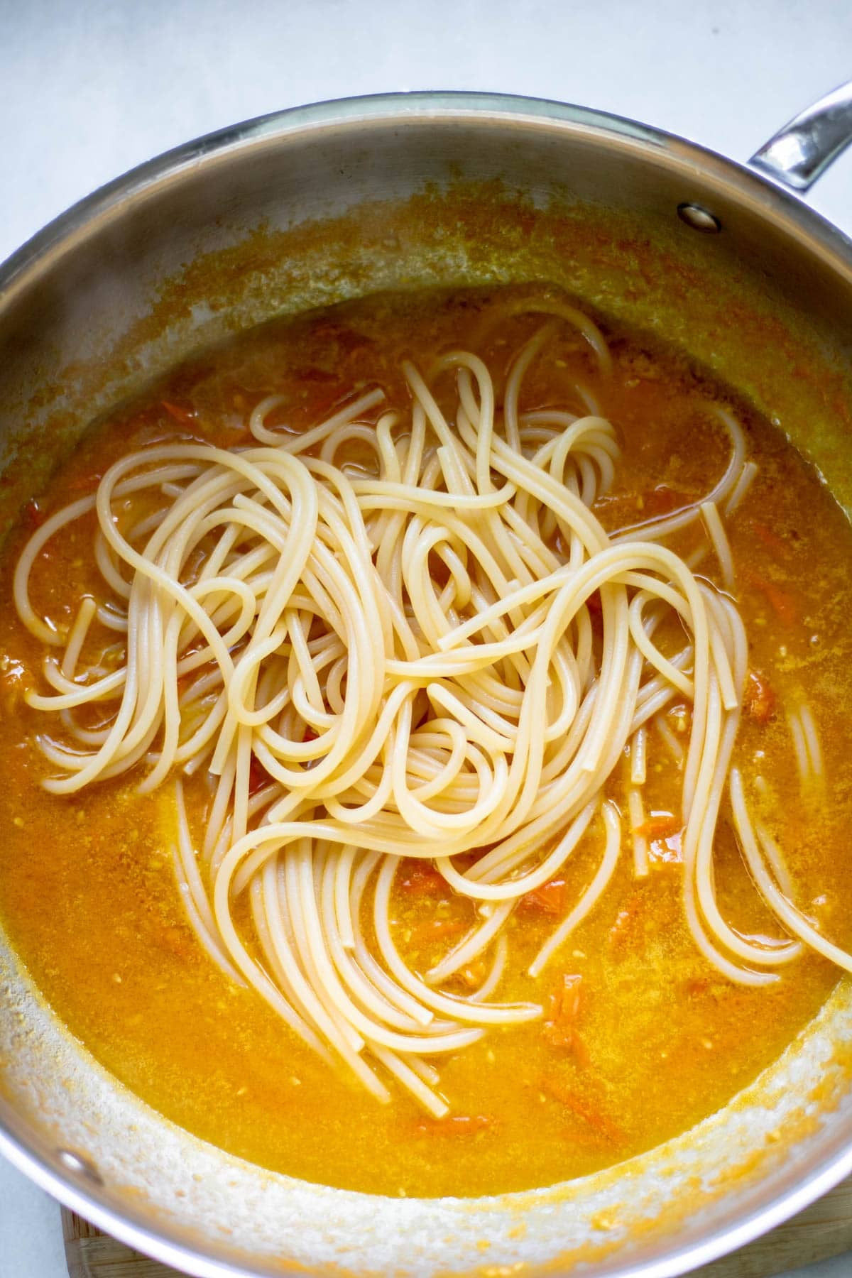 noodles added to a pan of sungold tomato pasta sauce