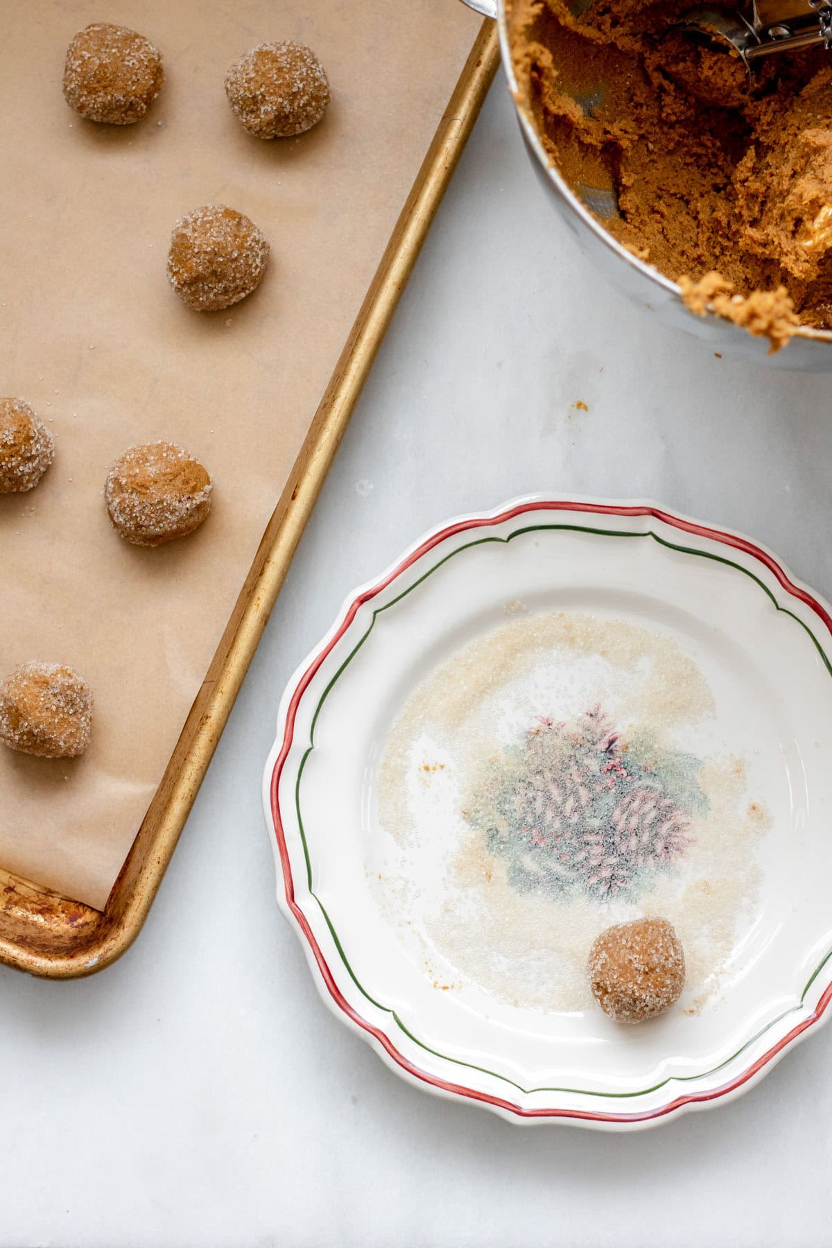 rolling gluten free molasses cookies in sugar and placing on sheet tray