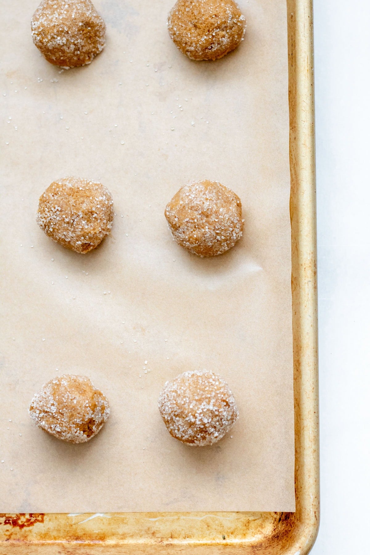 rolling gluten free molasses cookies in sugar and placing on sheet tray