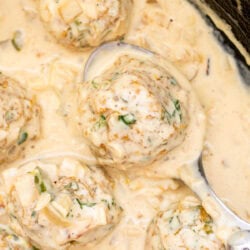 spoon holding a meatball in a creamy sauce