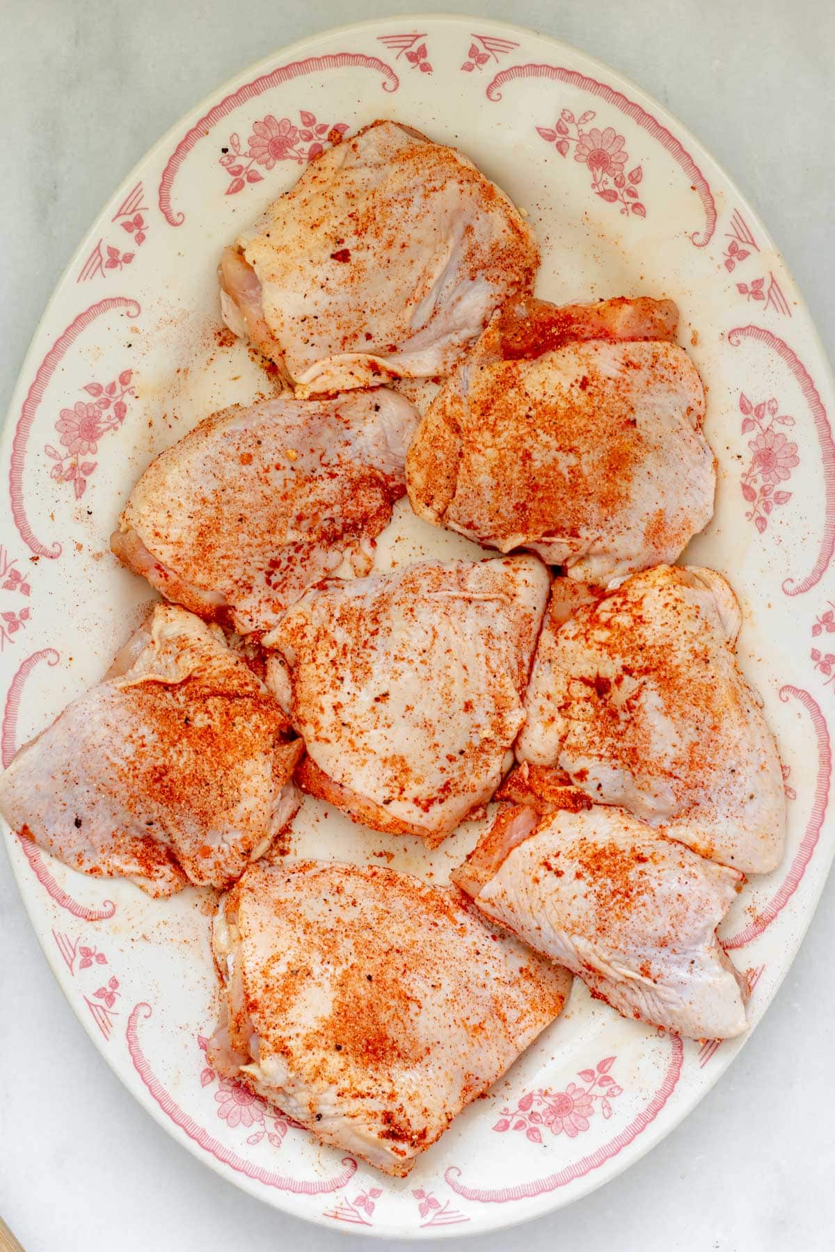 seasoned raw chicken breasts on a white and red plate