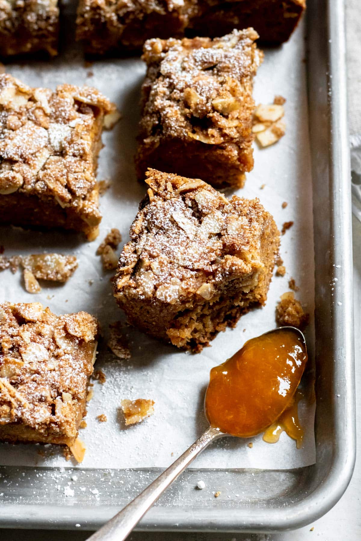 Almond Coffee Cake slices in a silver sheet pan with a spoonful of jam