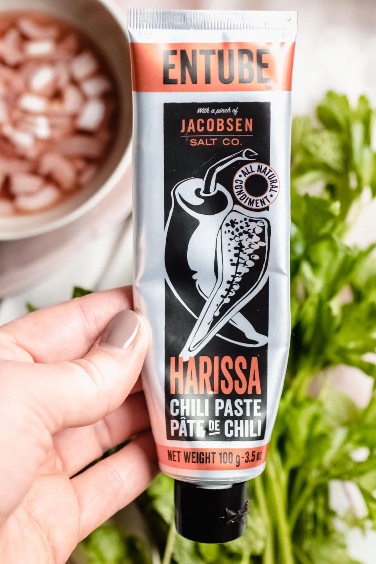 hand holding a tube of harissa chili paste