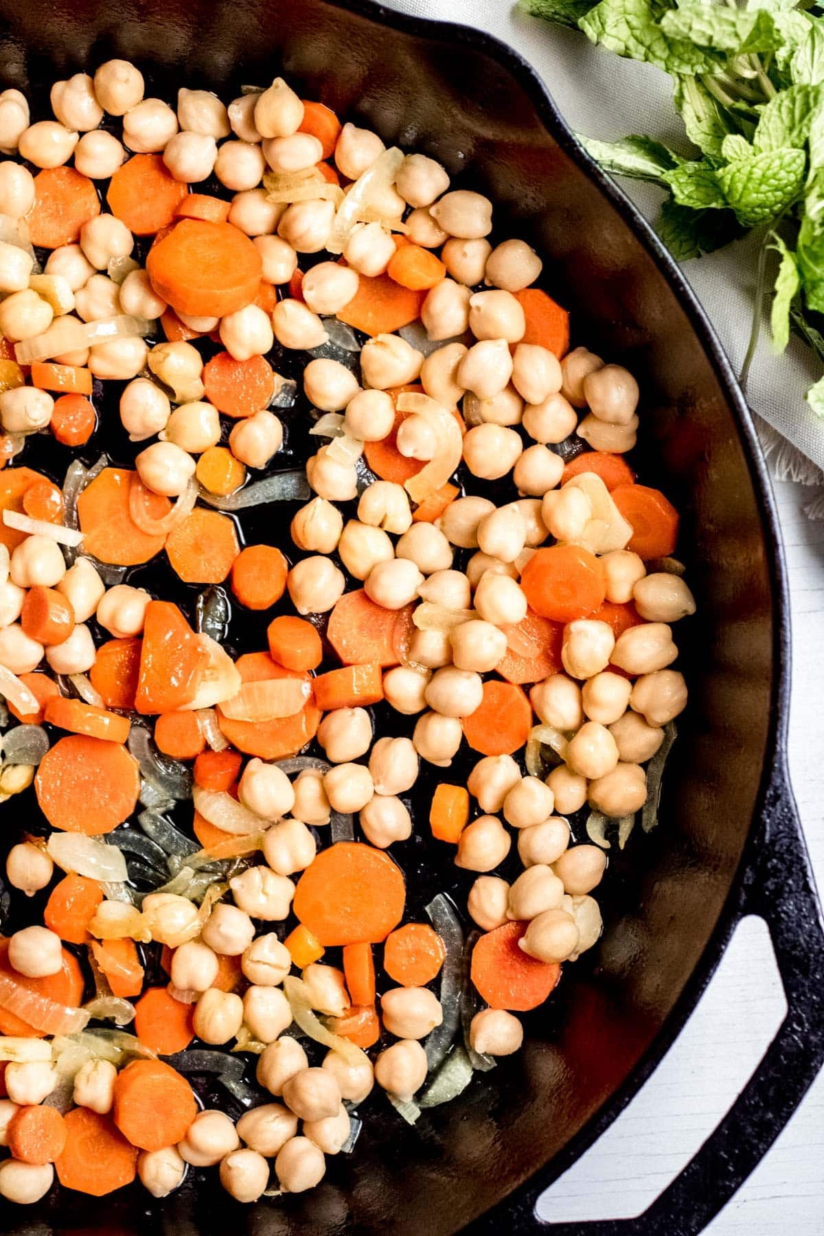 cooking chickpeas, carrot slices and onion in a pan