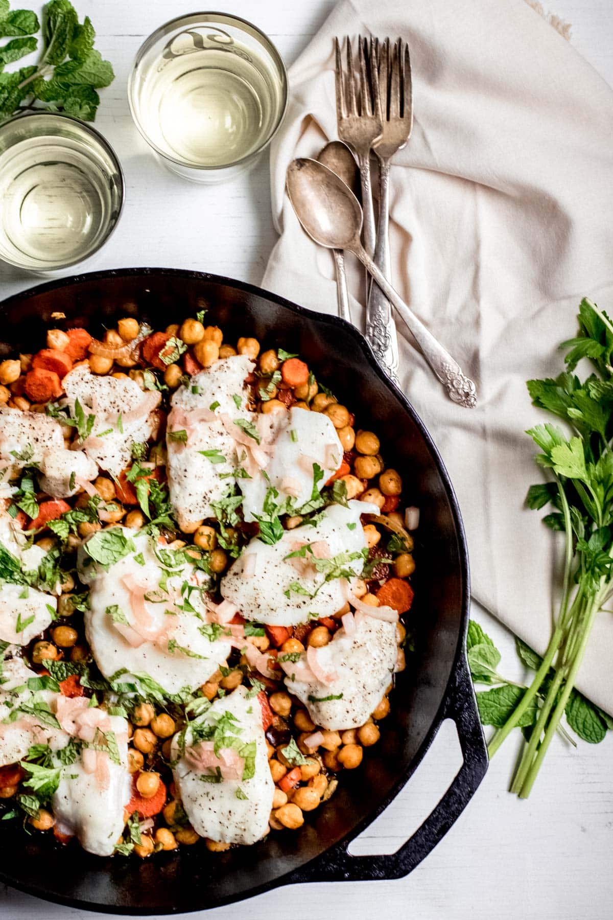top down view of a cast iron pan with roasted veggies and halibut on top