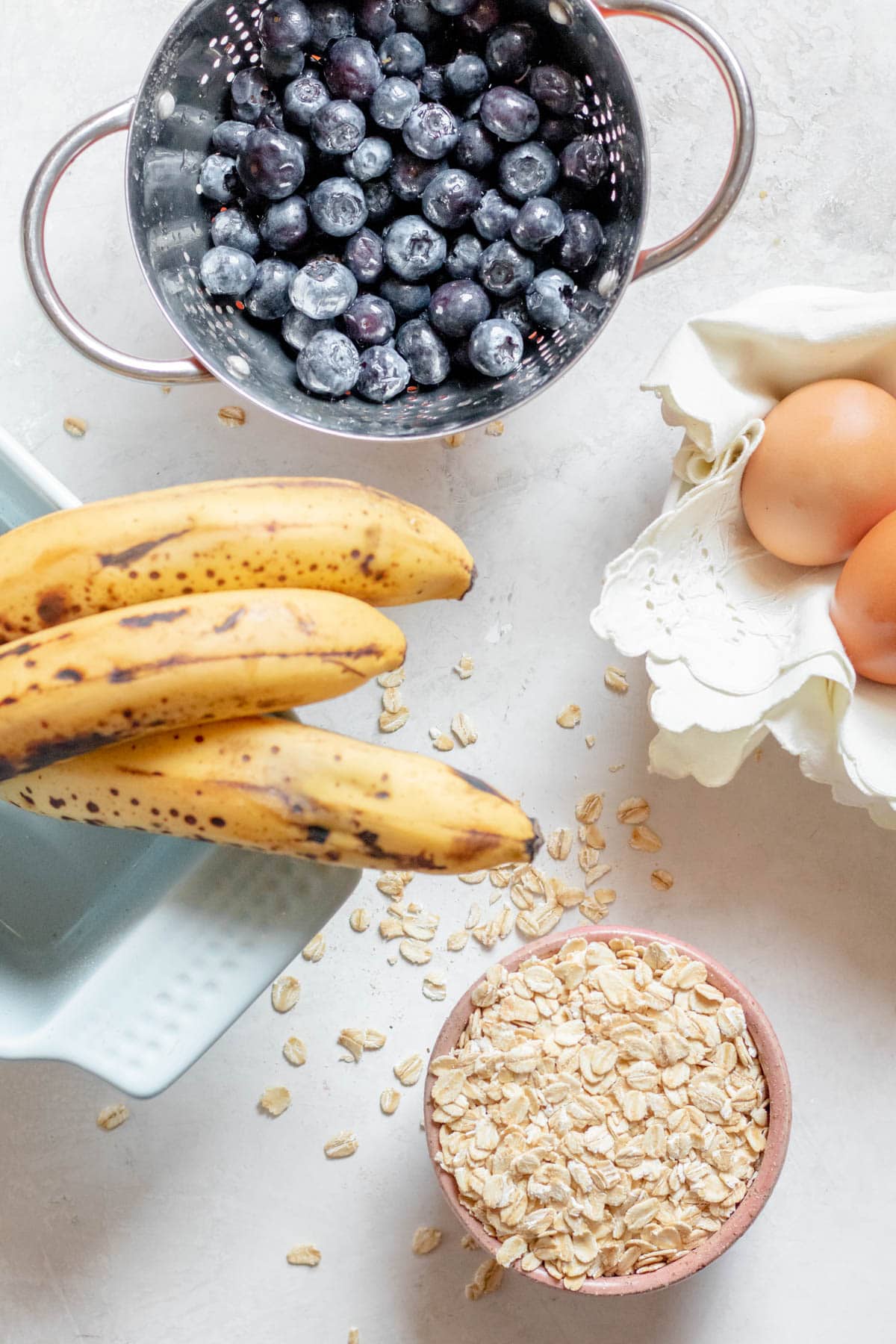 blueberries, bananas, oats and eggs on a table