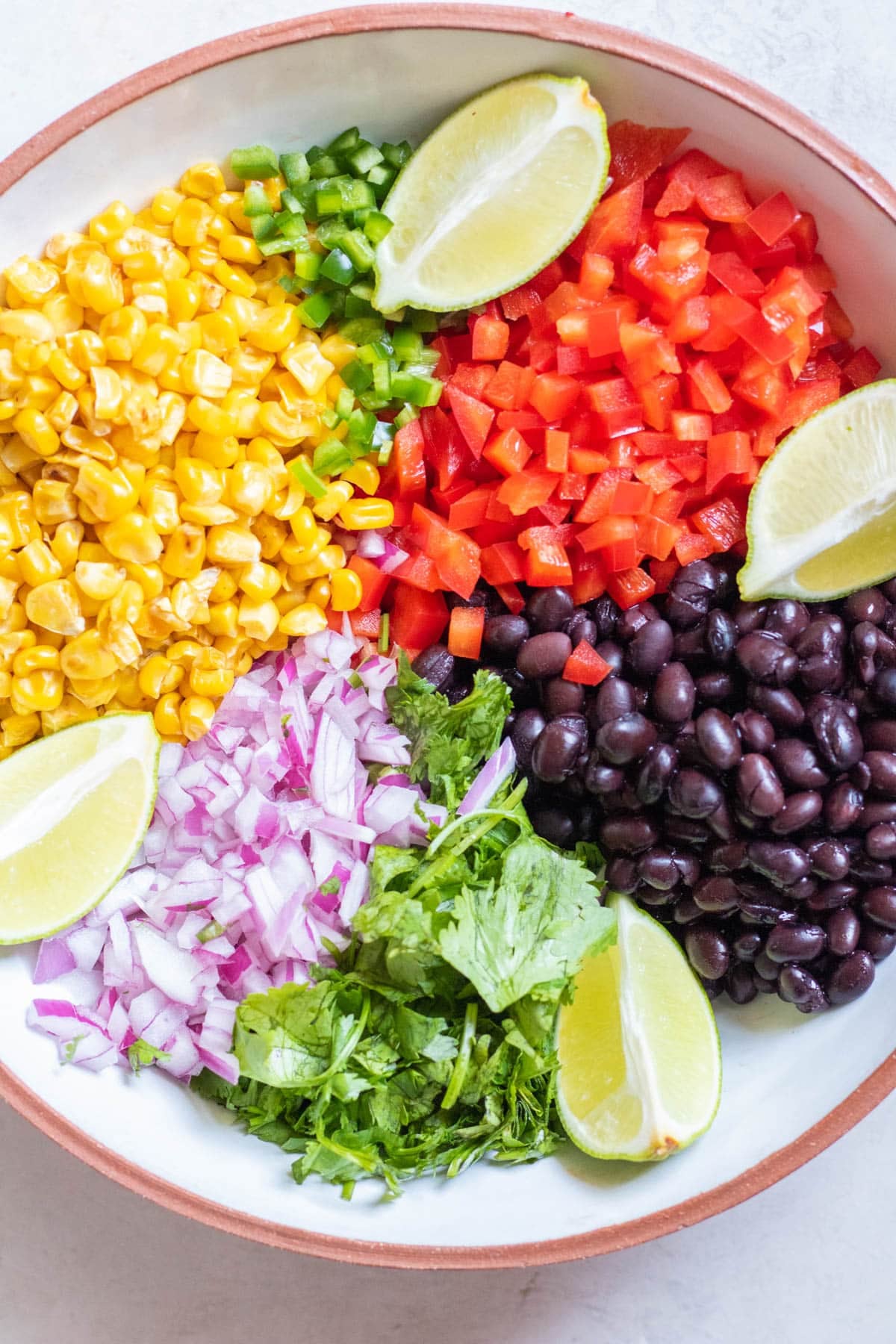 corn, chopped bell pepper, black beans, red chopped onion in a bowl