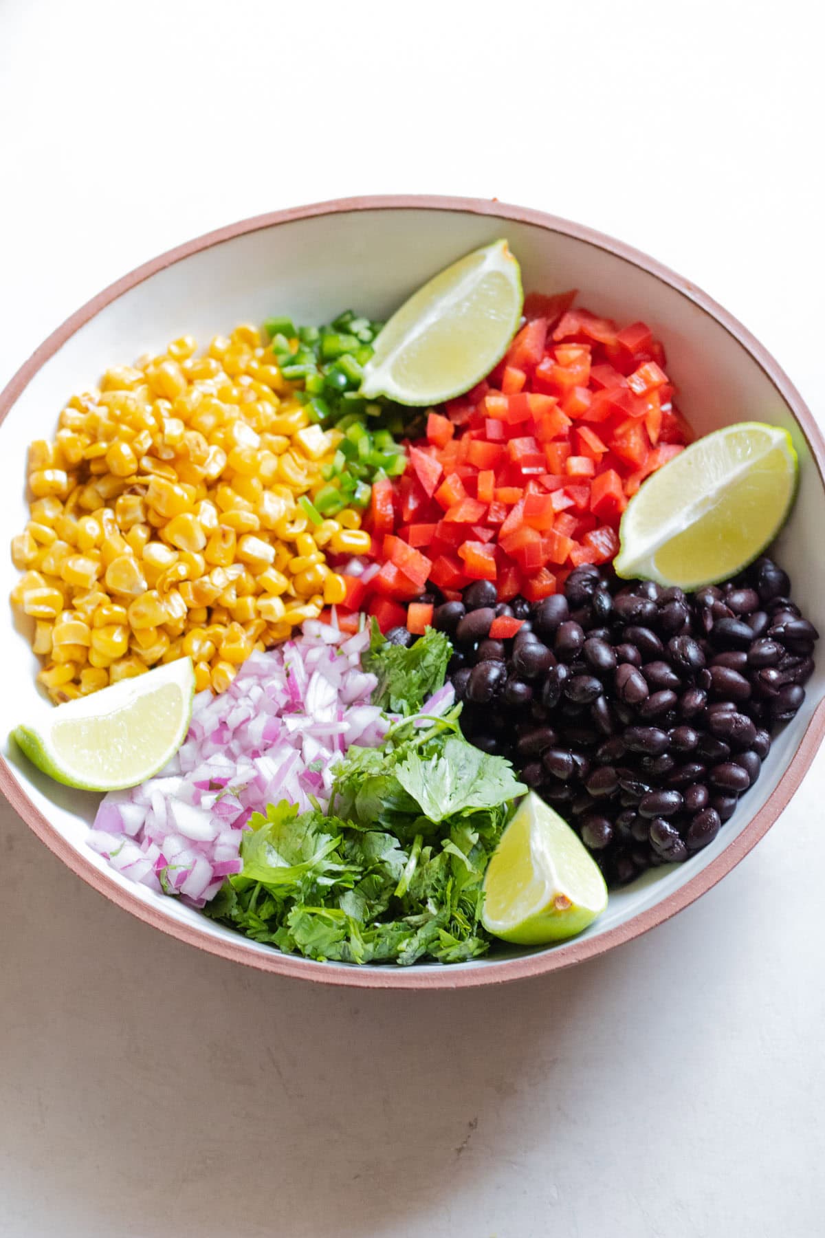 corn, chopped bell pepper, black beans, red chopped onion in a bowl
