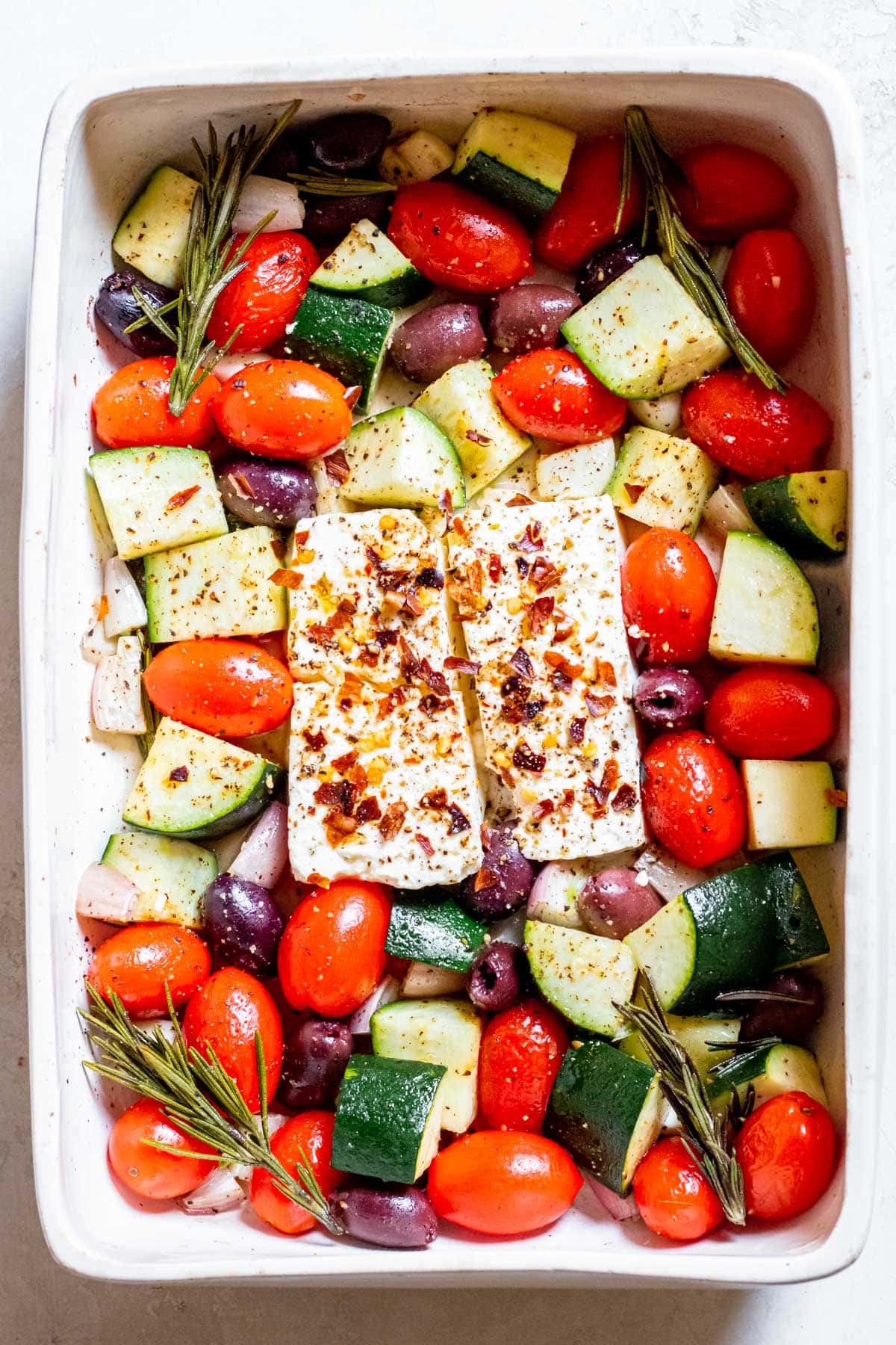 raw feta and veggies in a baking dish