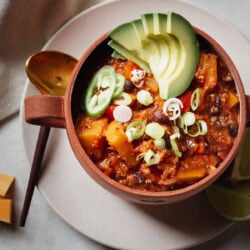 Healthy Quinoa Butternut Squash Chili with avocado slices in a red soup bowl