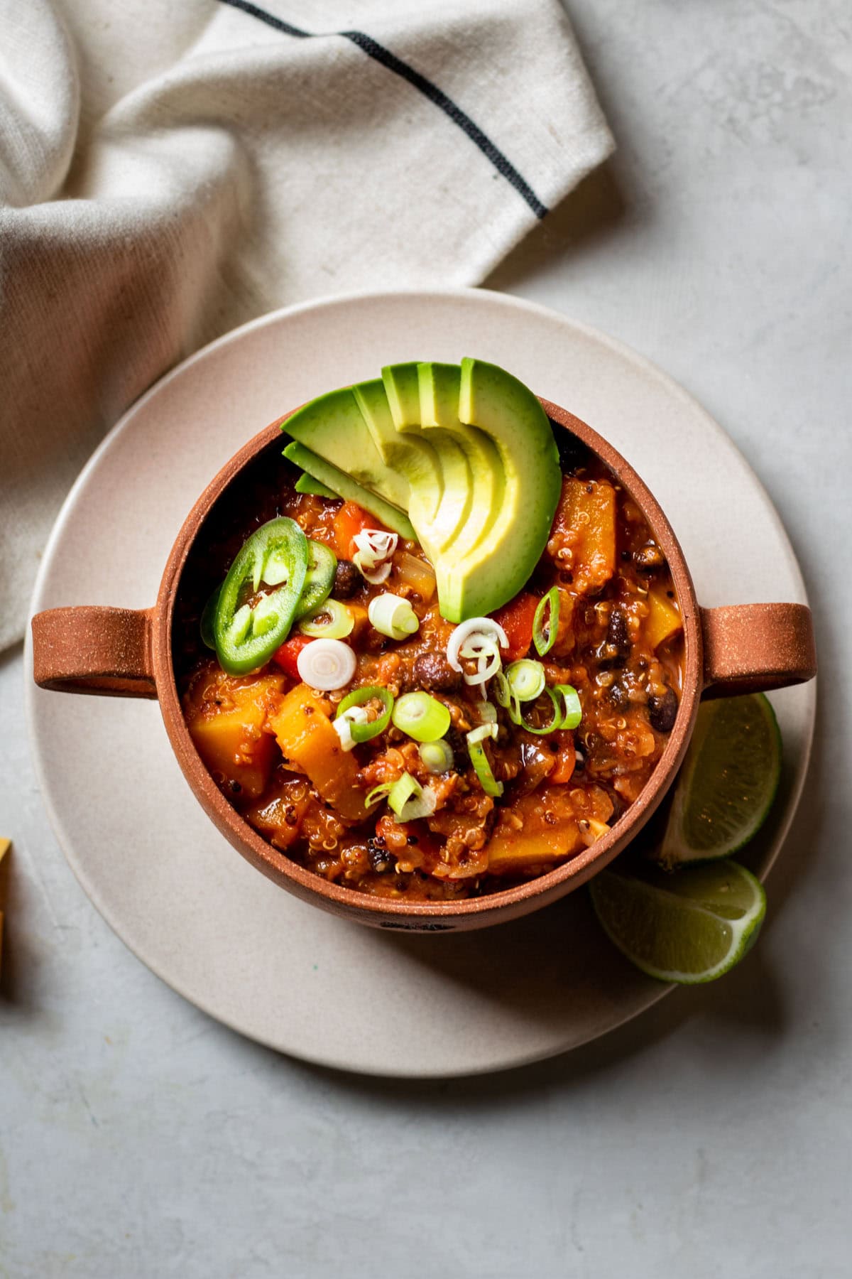 Healthy Quinoa Butternut Squash Chili with avocado slices in a red soup bowl