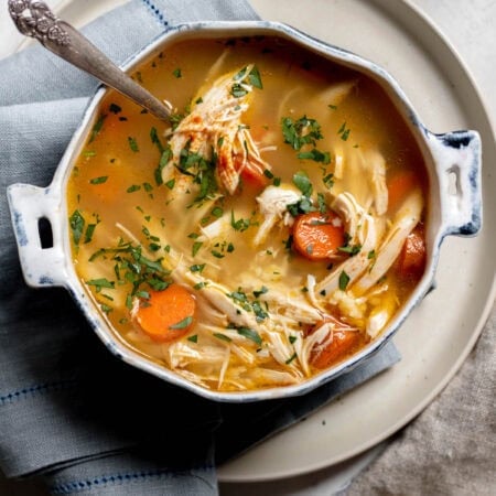 bowl of chicken noodle soup on a white plate