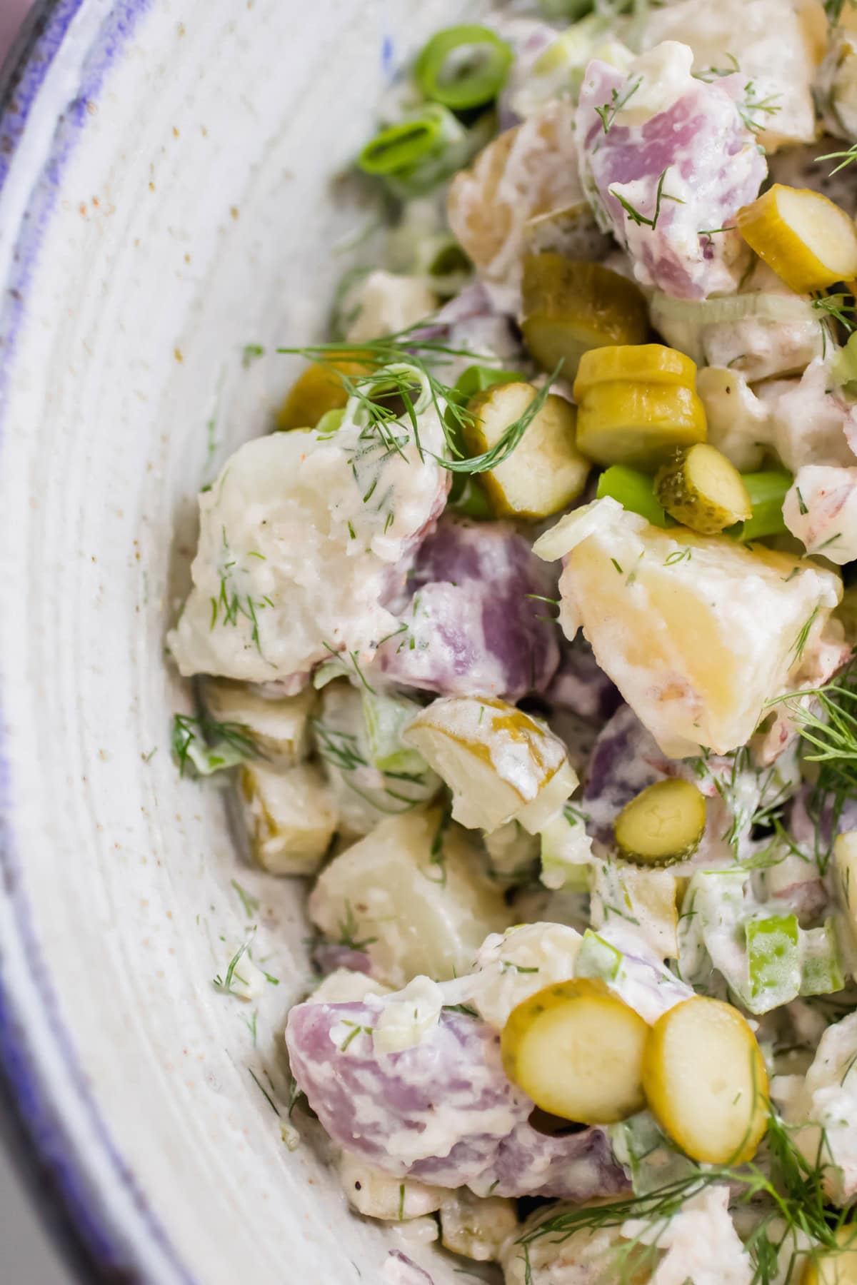 close up of pickle potato salad in a blue and white bowl