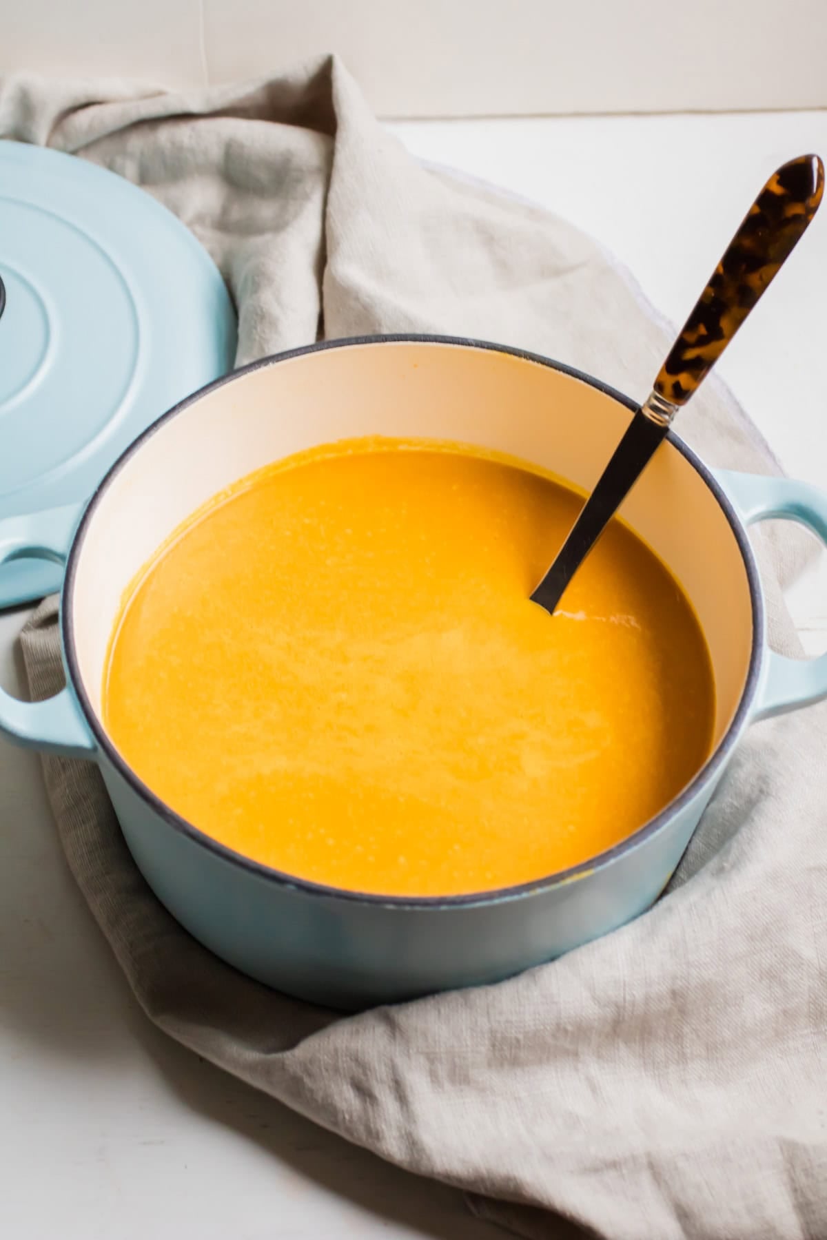 a large pot full of carrot soup with a ladle