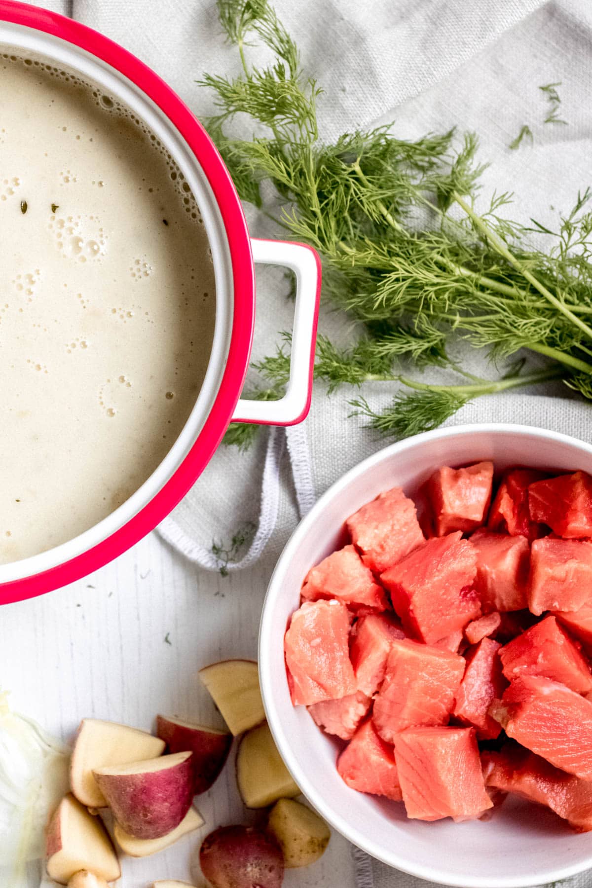 wild salmon chunks in a bowl next to chopped potatoes and dill