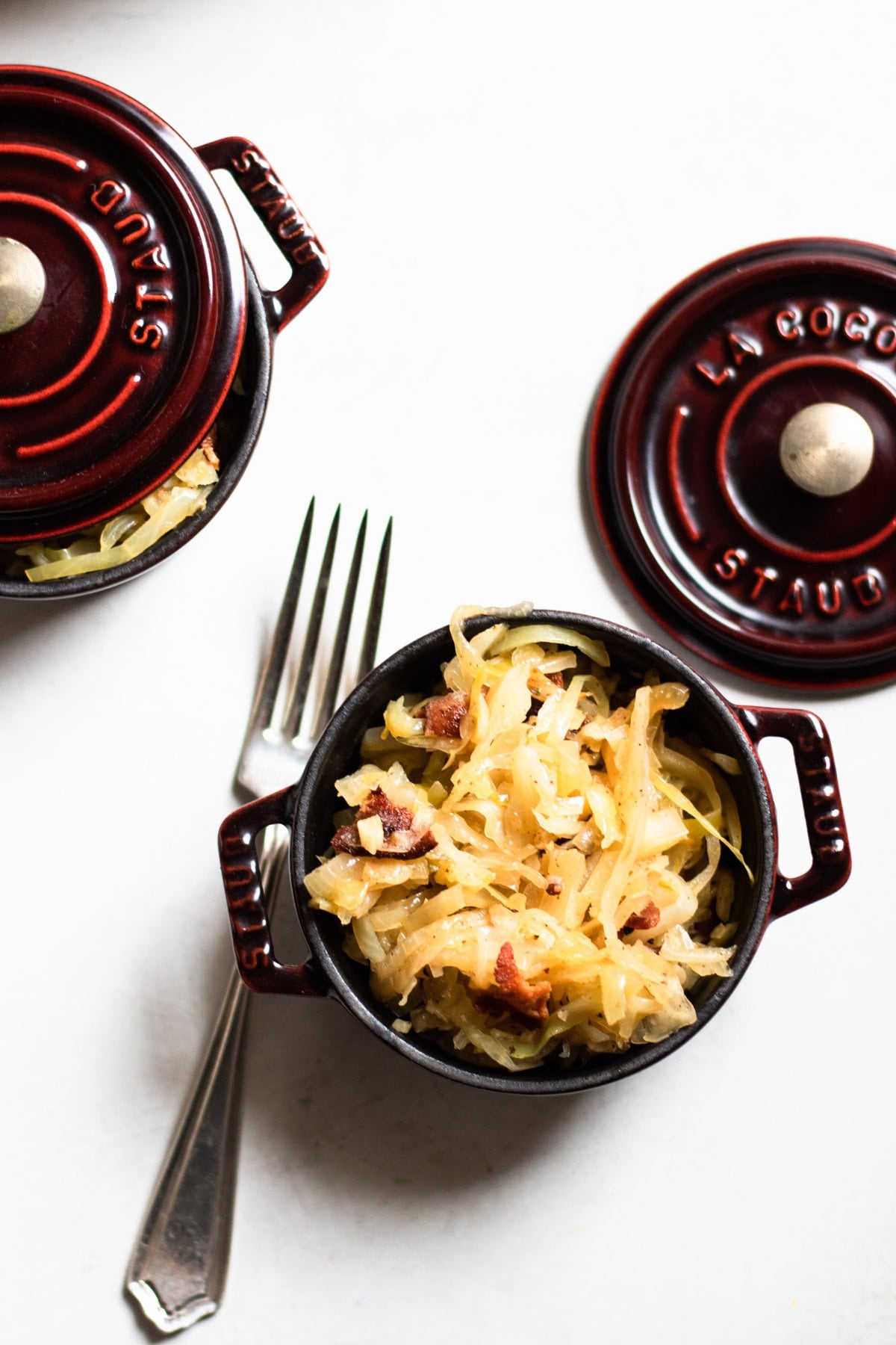 two bowls of Cabbage sauteed with crispy bacon and tangy sauerkraut on a table