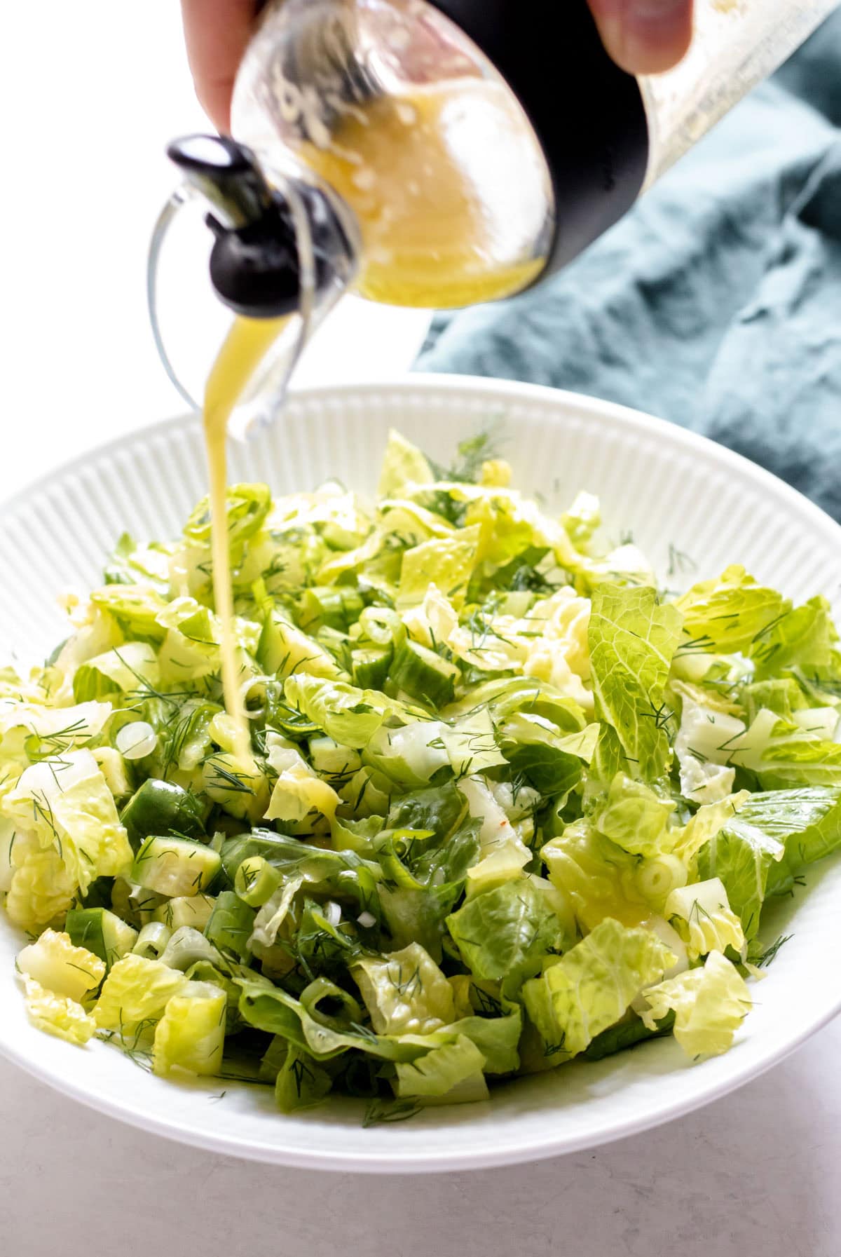 pouring dressing on shredded romaine lettuce