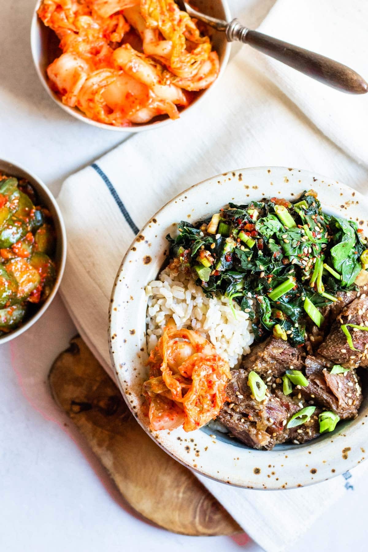 a bowl of korean beef, kale, rice and kimchi