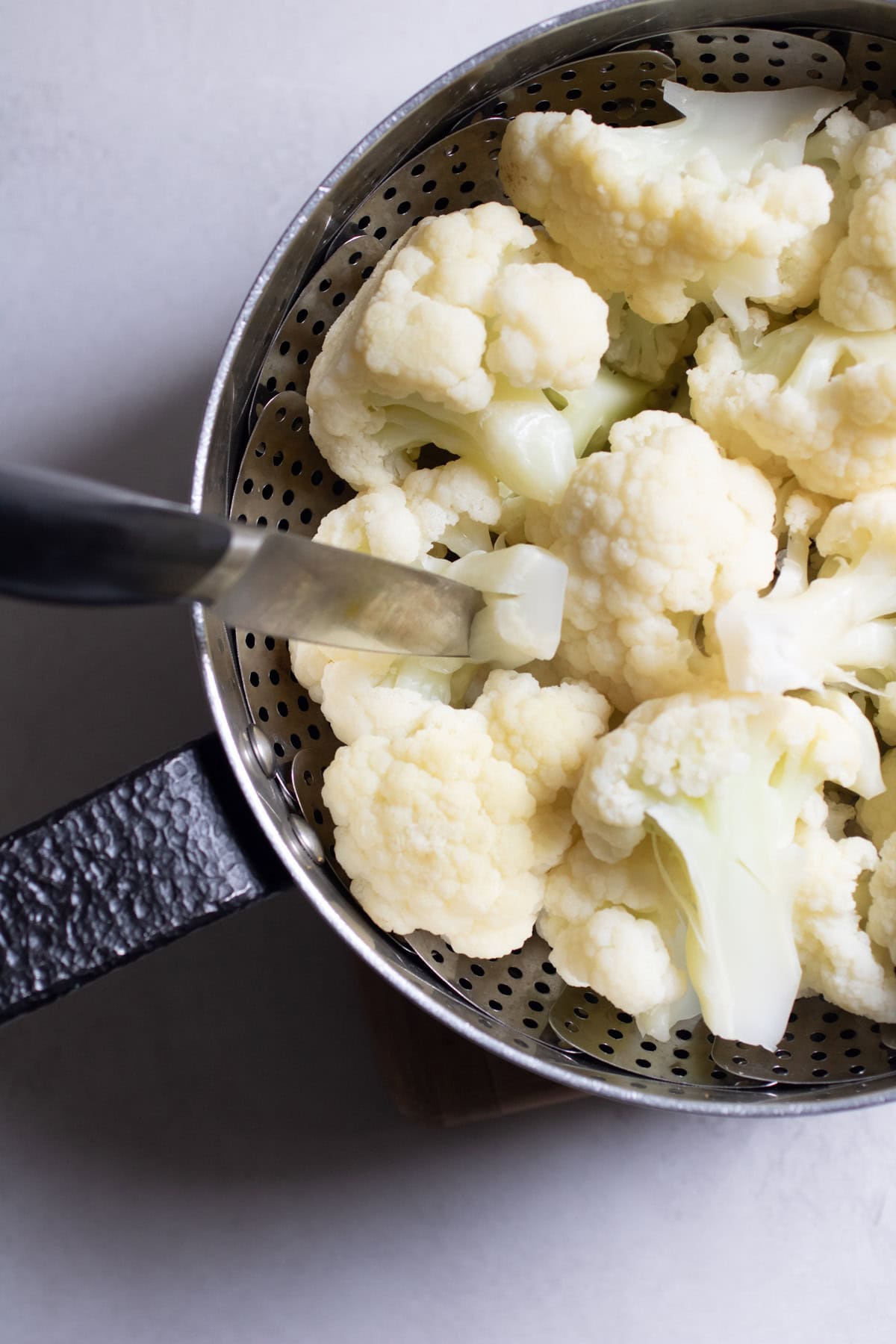 steamed cauliflower florets in a steamer basket