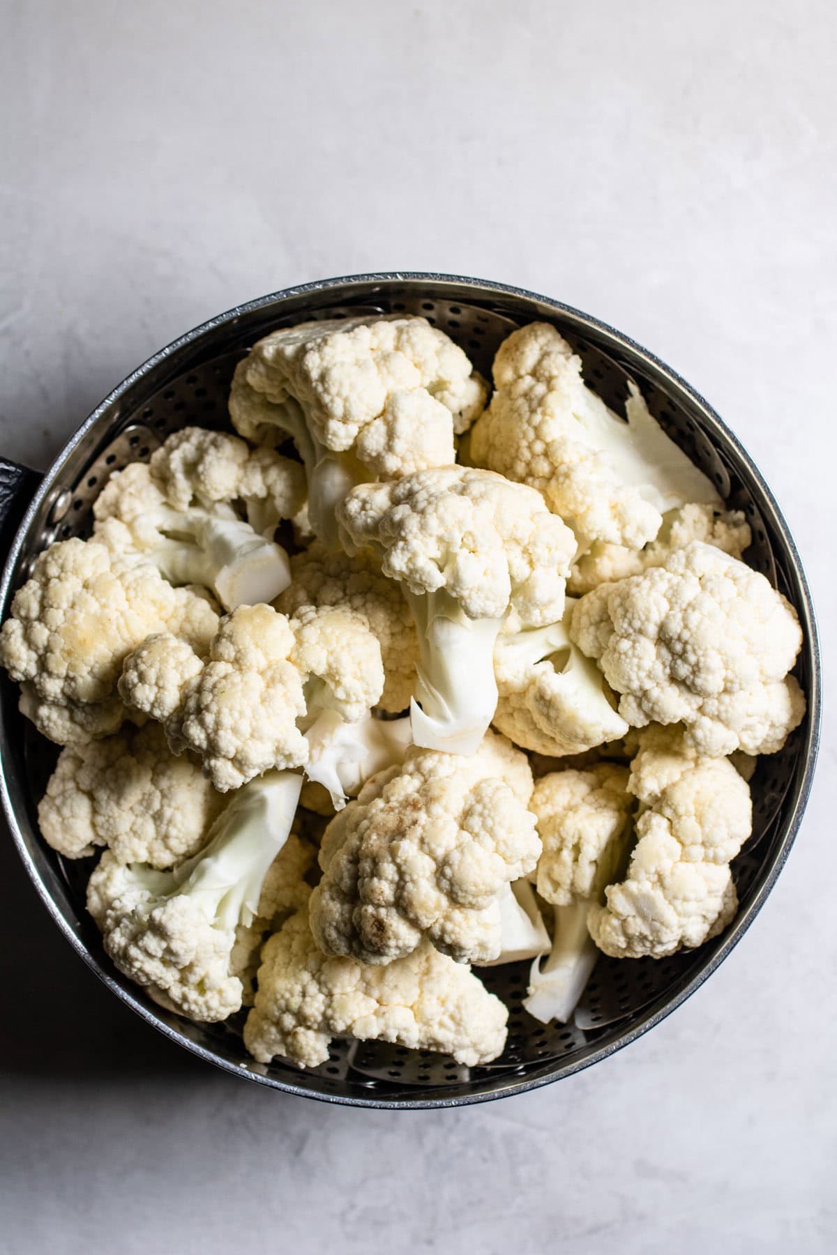 raw cauliflower florets in a steamer basket