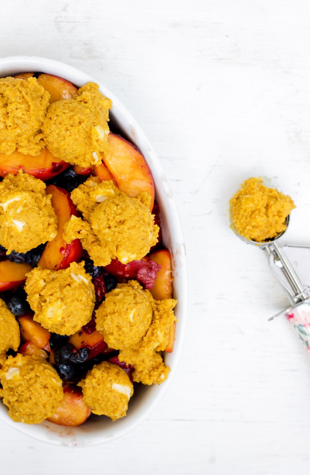 placing golden milk biscuit dough balls on top of fruit