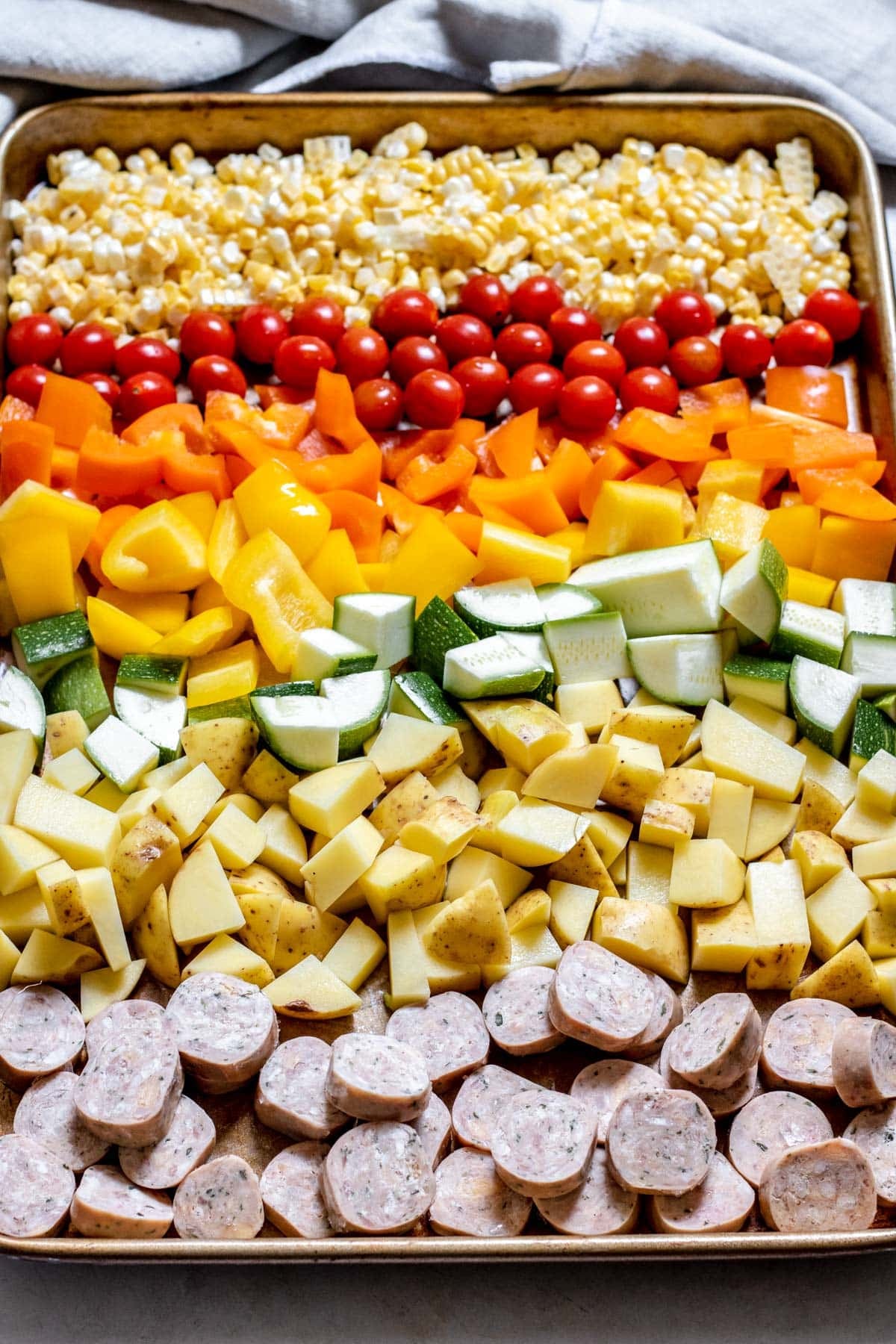 chopped vetegables and sausage slices in a sheet pan
