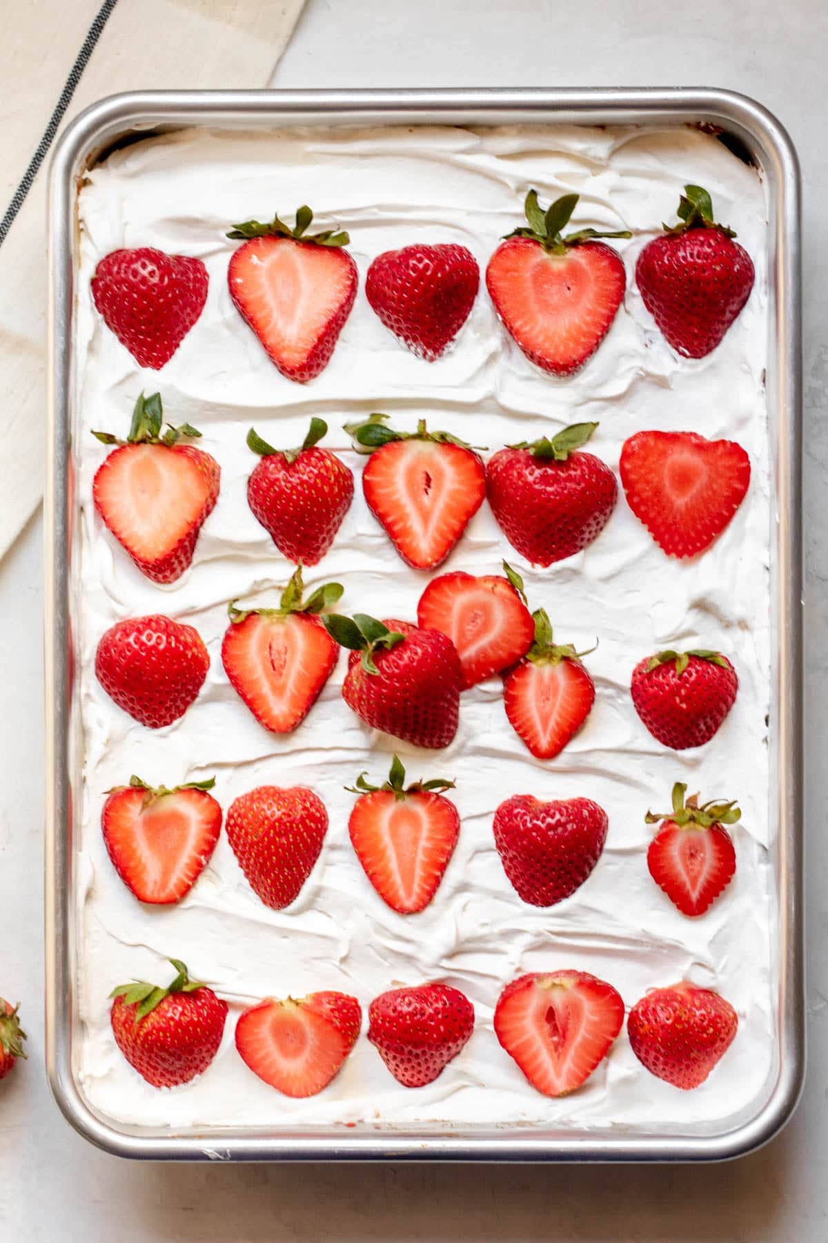halved strawberries and frosting on top of the cake