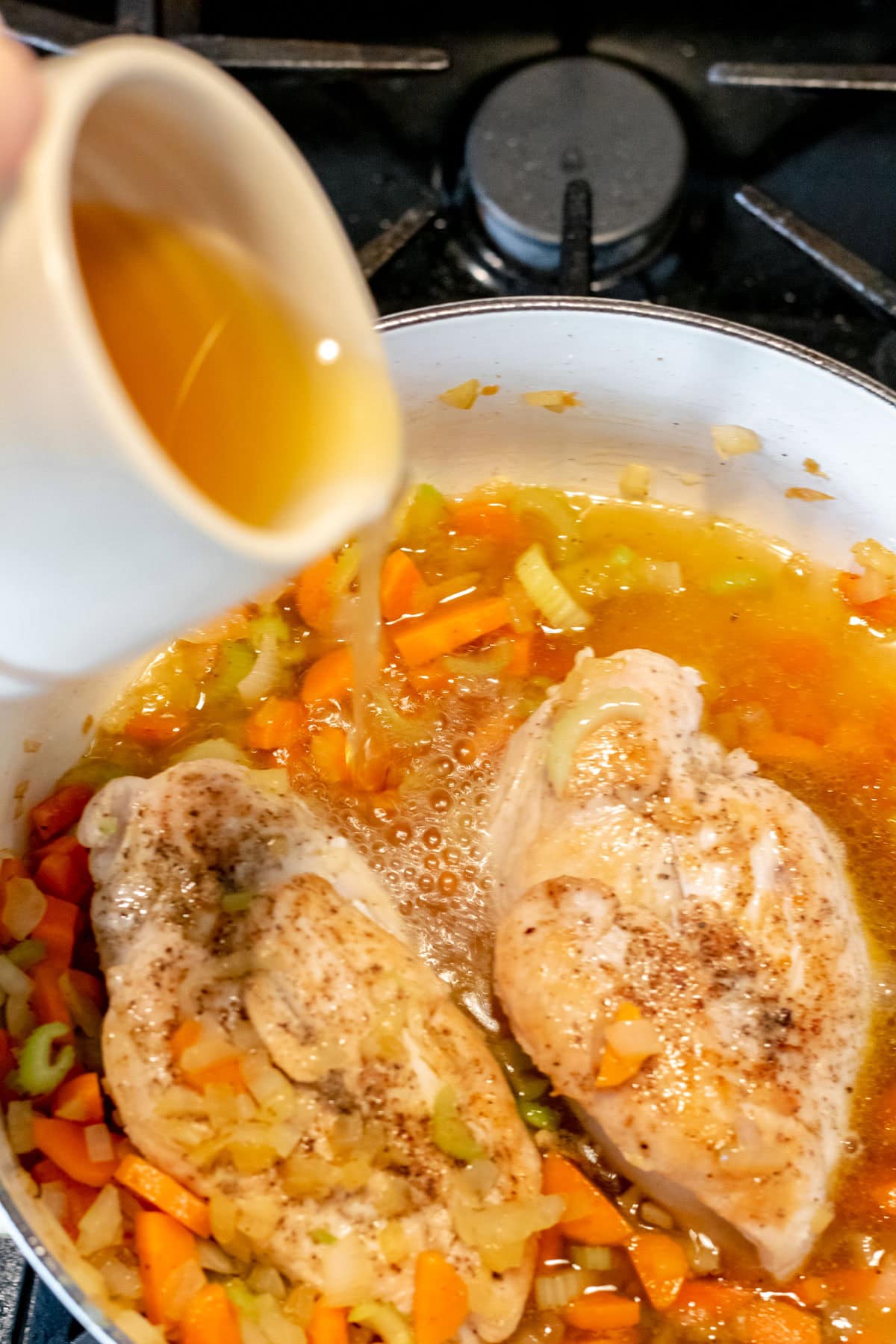 pouring chicken stock in the pan