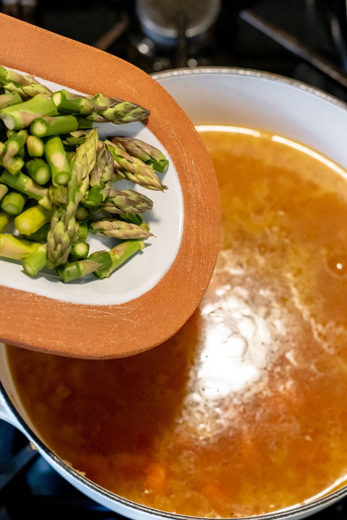 adding chopped asparagus to soup