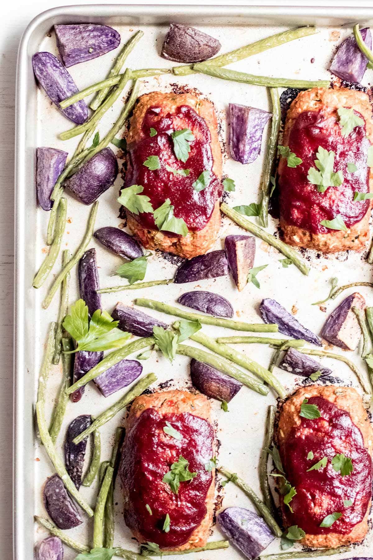 four mini meatloafs on a baking sheet