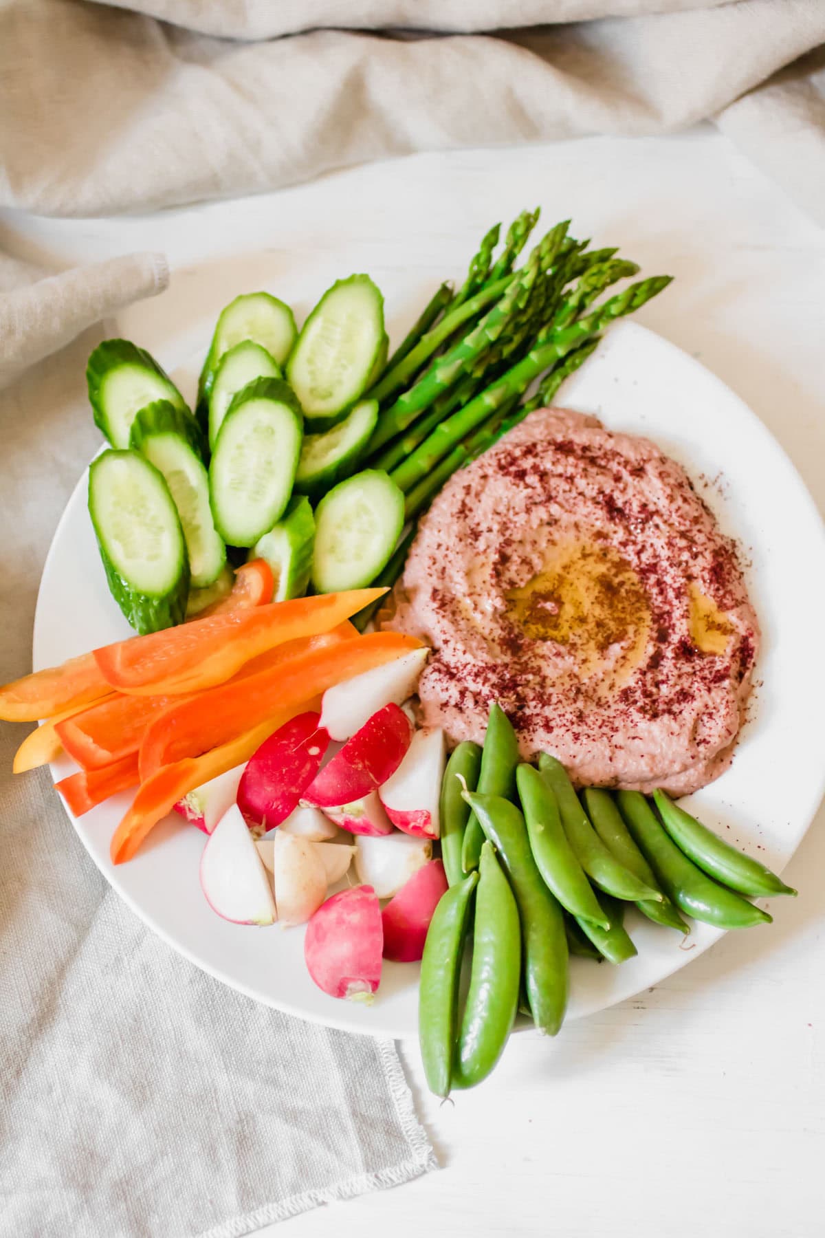 Beet Sumac Hummus and sliced veggies on a plate