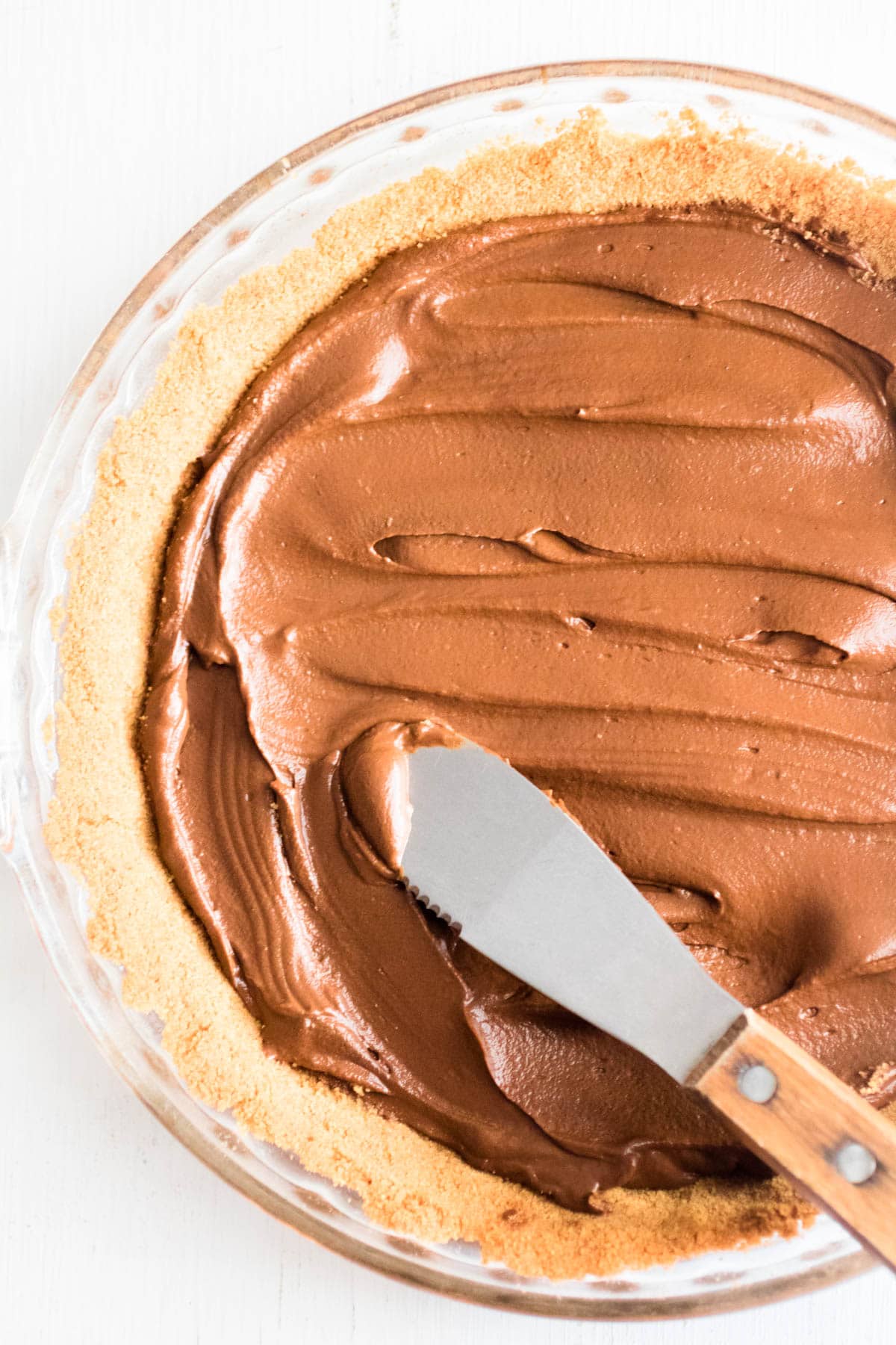 spreading chocolate avocado pudding on pie crust