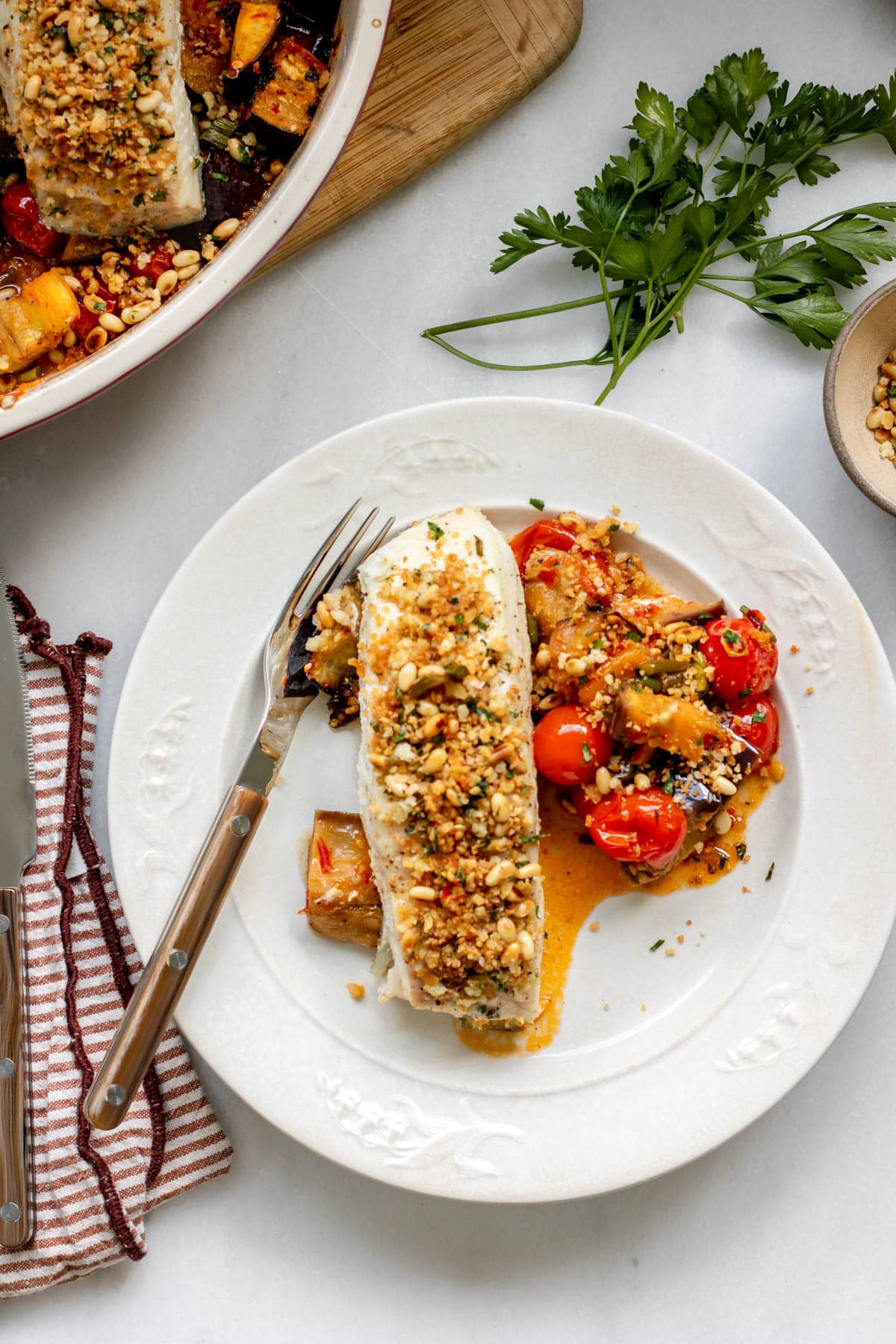 baked halibut with roasted eggplants on a white plate