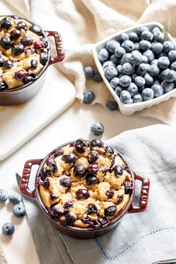 Close up shot of baked blueberry oatmeal in a purple pot on a white background