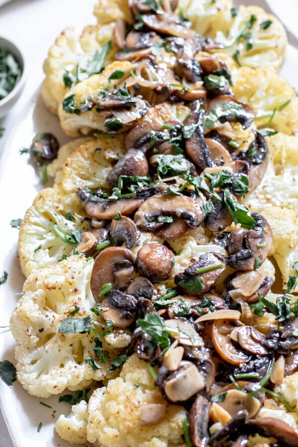close up shot of cauliflower steak with a mushroom marsala sauce sprinkled with parsley