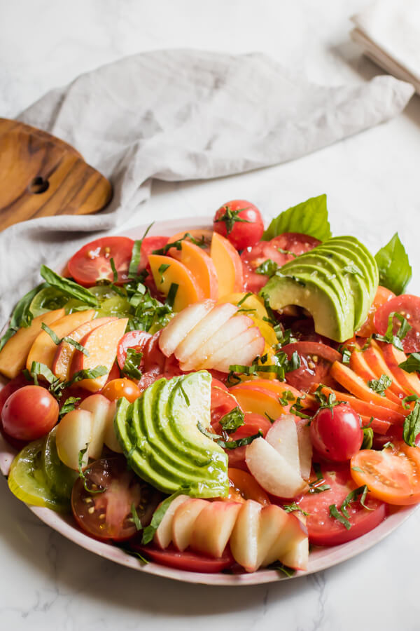 A fresh heirloom tomato salad with juicy sweet peaches, creamy avocado, and fresh herbs. This healthy, simple salad is the very representation of savoring the final weeks of summer using only seasonal local produce. 