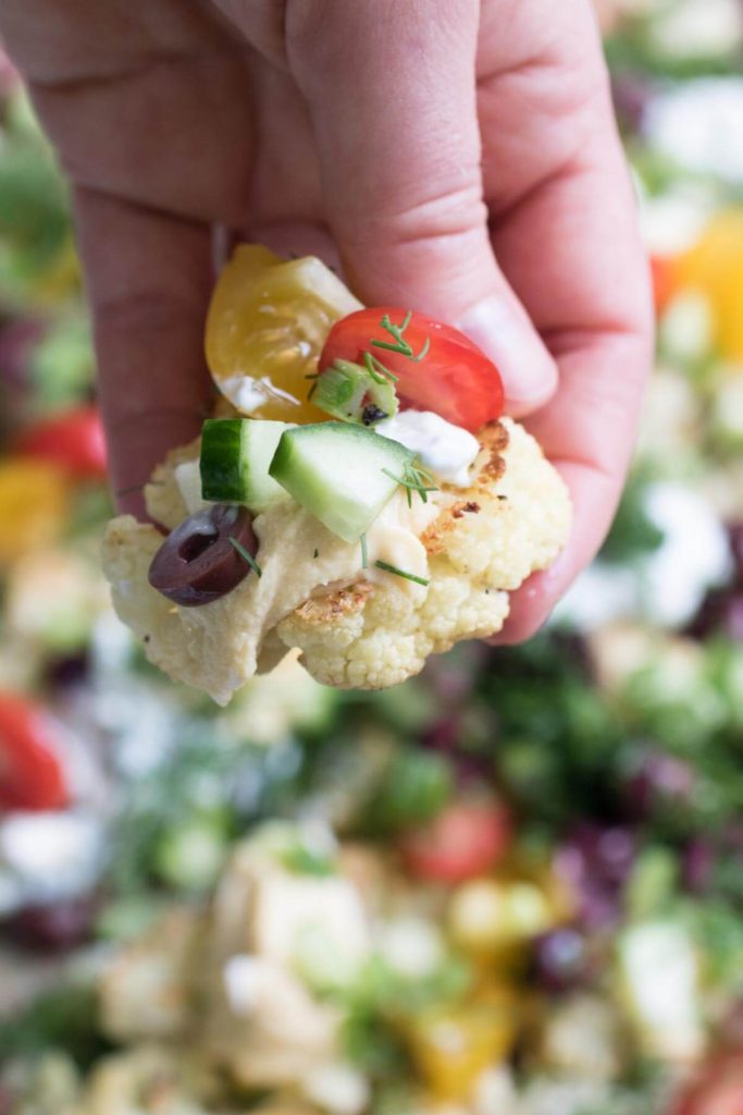 Loaded Mediterranean Cauliflower Nachos are piled high with creamy feta cheese, crunchy cucumbers, hummus, olives, tzatziki sauce and more! So delicious you won't want to share. | abraskitchen.com 