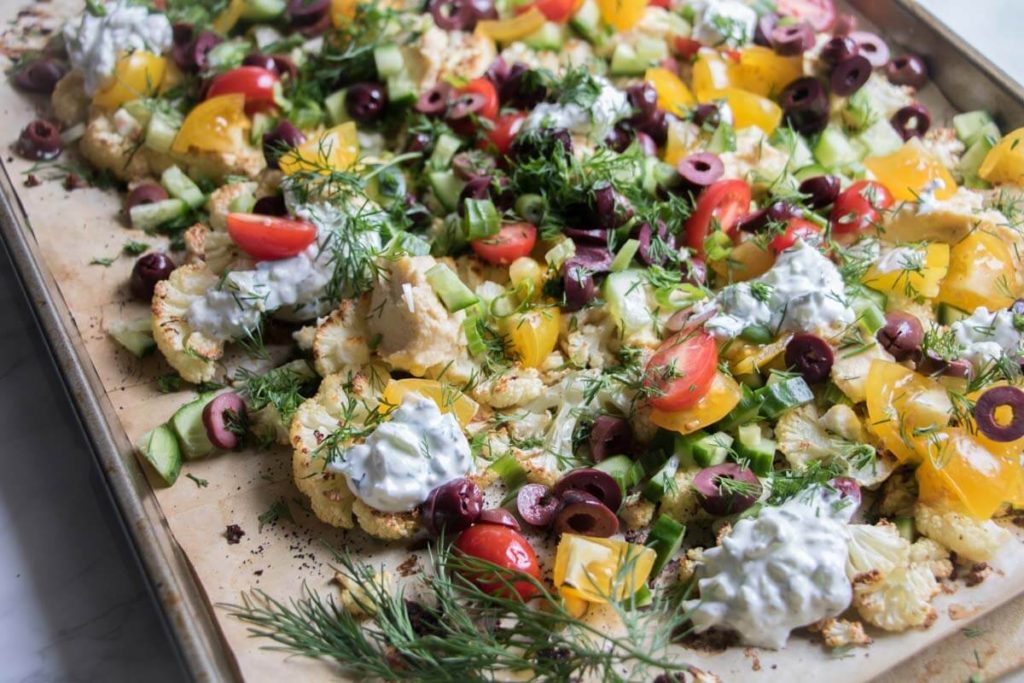 Loaded Mediterranean Cauliflower Nachos are piled high with creamy feta cheese, crunchy cucumbers, hummus, olives, tzatziki sauce and more! So delicious you won't want to share. | abraskitchen.com 