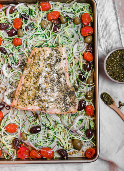 Mediterranean Sheet Pan Salmon with Zucchini Noodles, 10 minutes to a healthy delicious dinner! Mediterranean spiced salmon nestled on a bed of zucchini noodles, olives, tomato, onion, and garlic. A few simple ingredients, one sheet pan, and 10 minutes in the oven. Paleo, Whole30, Gluten Free, Anti-inflammatory, good for you and delicious!