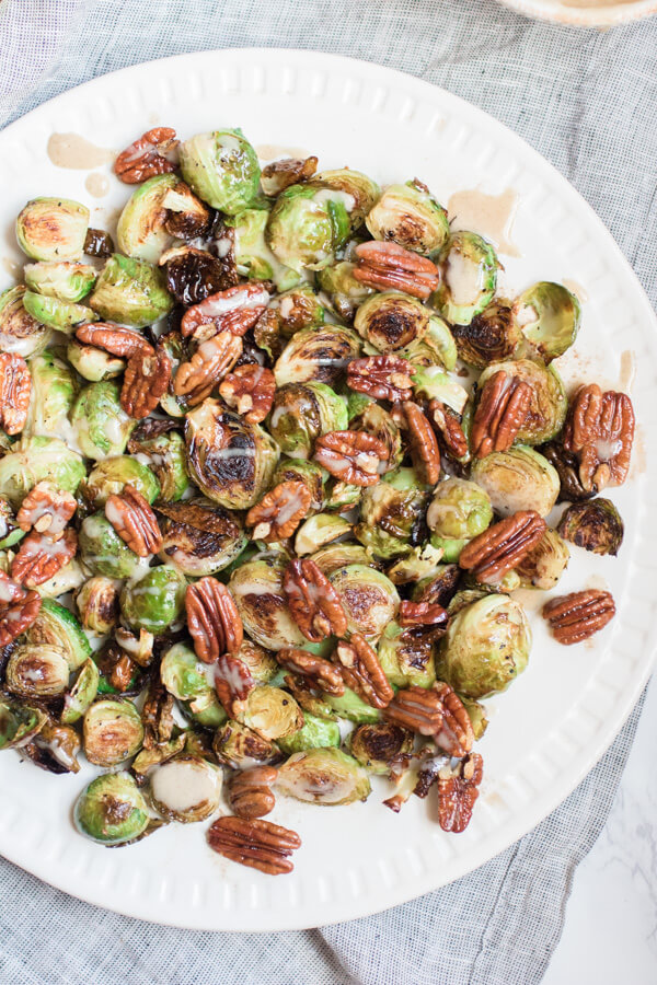 Gorgeous roasted Brussels sprouts tossed with crunchy pecans in a brown butter sauce and drizzled with a spiced maple tahini glaze.
