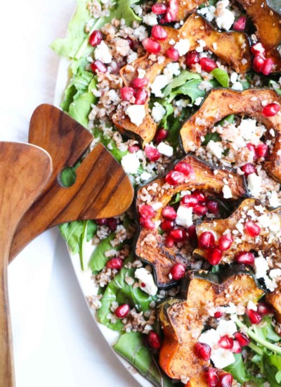 This festive (gluten free) Roasted Acorn Squash Salad with warm Buckwheat, Five-Spice Acorn Squash, Feta Cheese, and Pomegranate Seeds is full of healthy seasonal ingredients and a sweet and tangy maple dijon dressing. |Abraskitchen.com