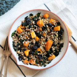 Butternut Squash and Kale Farro Salad with Dried Cherries and Pecans in white bowl on white background