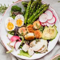 scallop nicoise salad on white bowl with asparagus and radishes and veggies