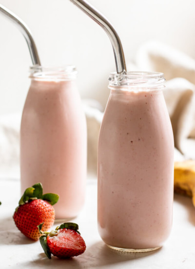 Strawberry Banana Adaptogen Smoothie in two glass jars with straws on white background